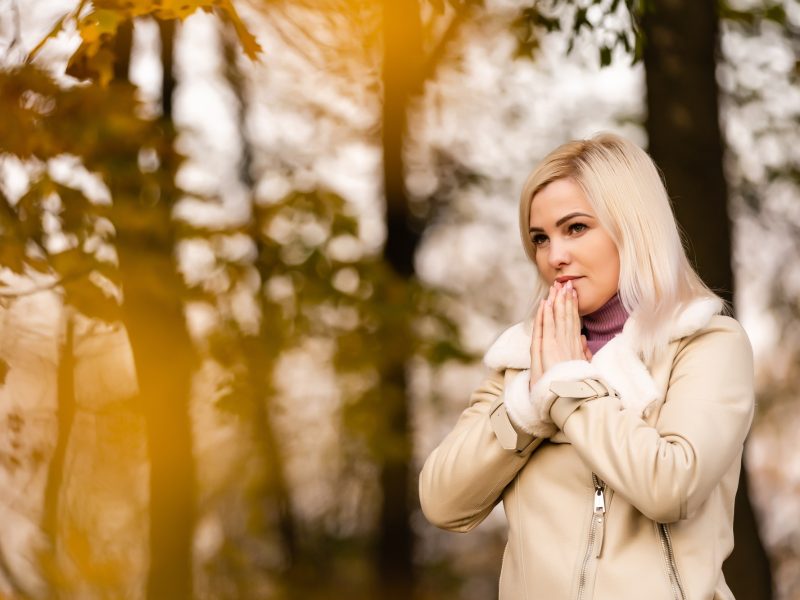 Attractive young woman is praying in the park hoping for better times to come. Concept for faith